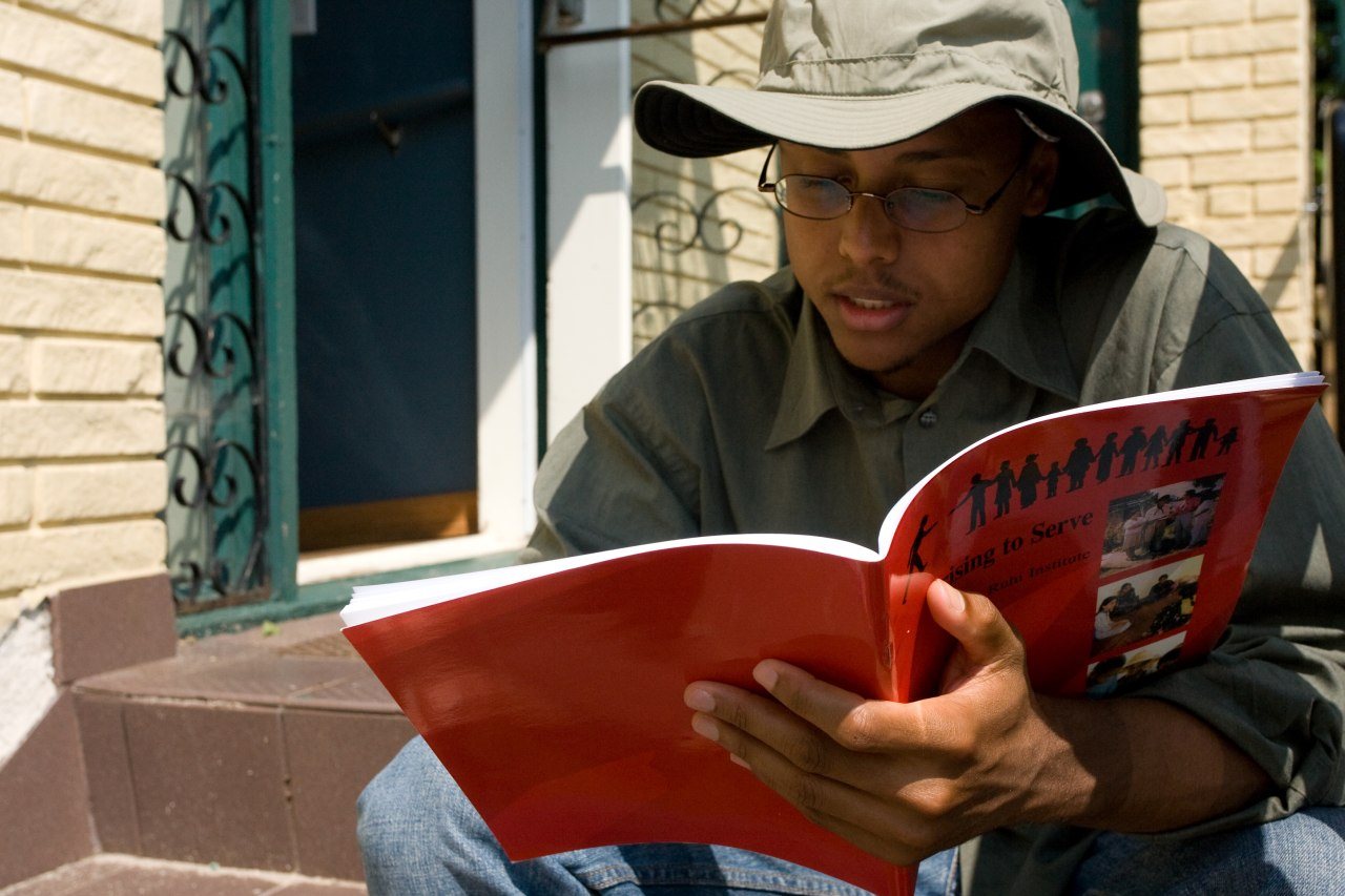 A person reading quietly outdoors in soft, warm daylight